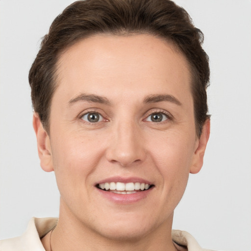 Joyful white young-adult female with short  brown hair and grey eyes