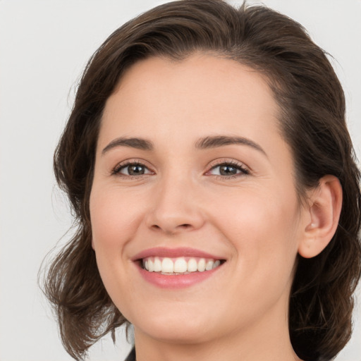 Joyful white young-adult female with medium  brown hair and green eyes