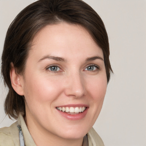 Joyful white young-adult female with medium  brown hair and grey eyes