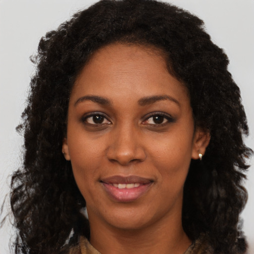 Joyful black young-adult female with long  brown hair and brown eyes