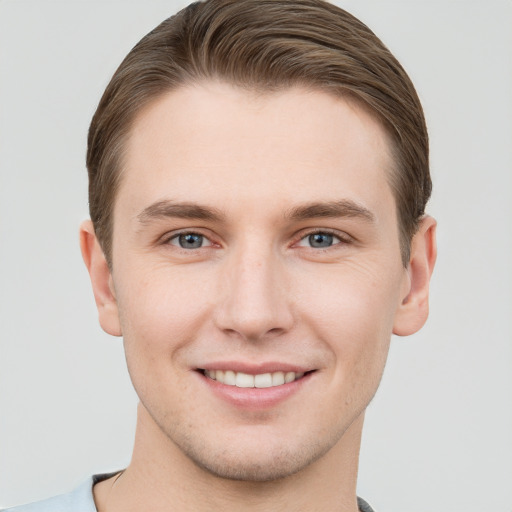 Joyful white young-adult male with short  brown hair and grey eyes