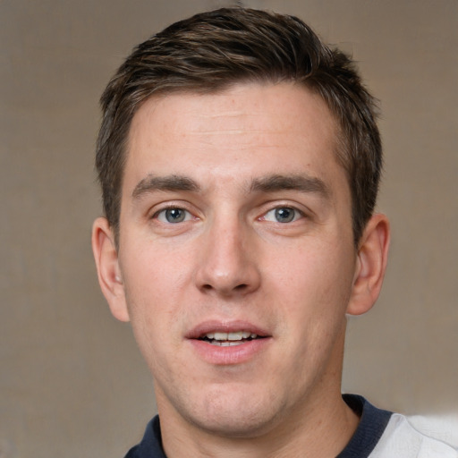 Joyful white young-adult male with short  brown hair and grey eyes