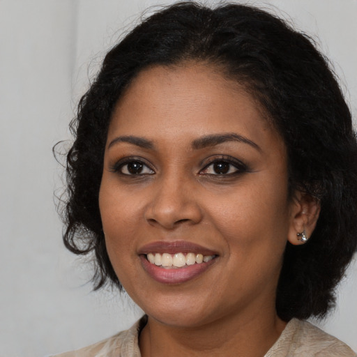 Joyful black young-adult female with long  brown hair and brown eyes