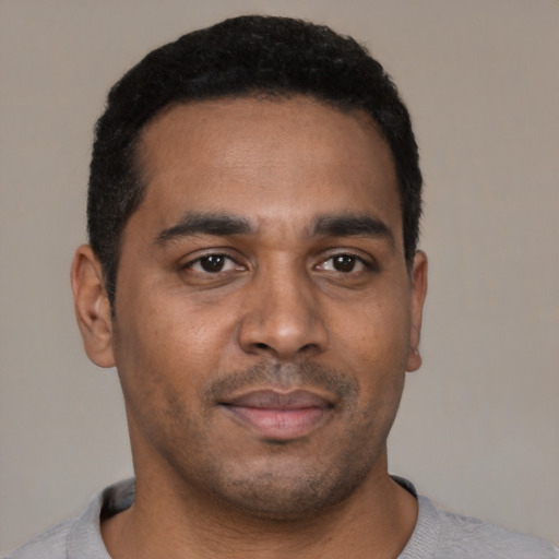 Joyful black young-adult male with short  brown hair and brown eyes