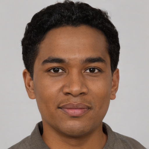 Joyful black young-adult male with short  black hair and brown eyes