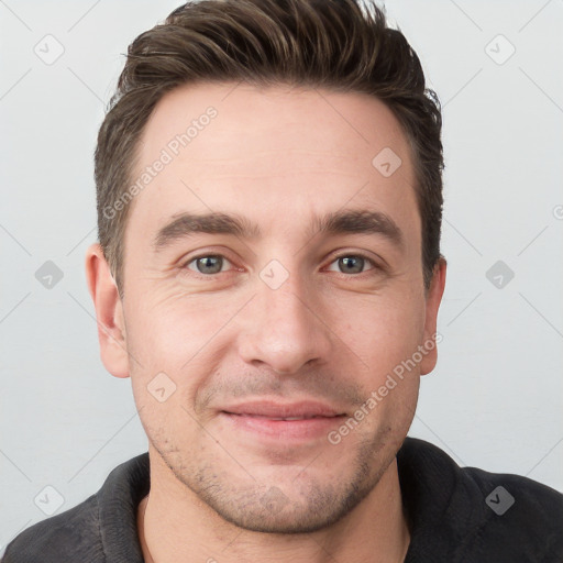 Joyful white young-adult male with short  brown hair and grey eyes