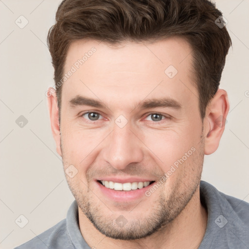 Joyful white young-adult male with short  brown hair and grey eyes