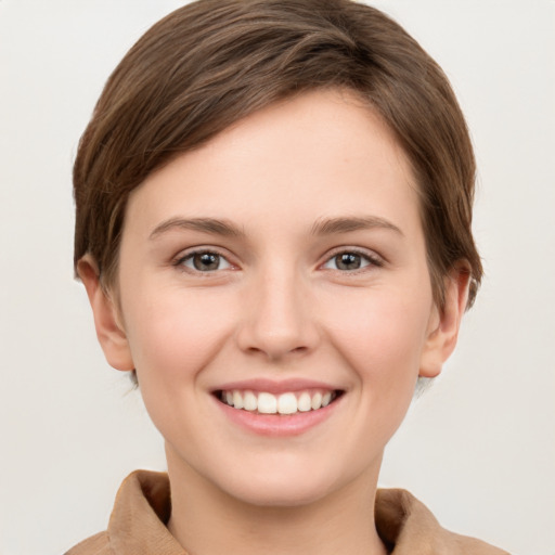 Joyful white young-adult female with short  brown hair and grey eyes