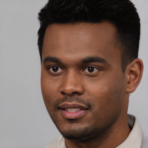 Joyful black young-adult male with short  black hair and brown eyes