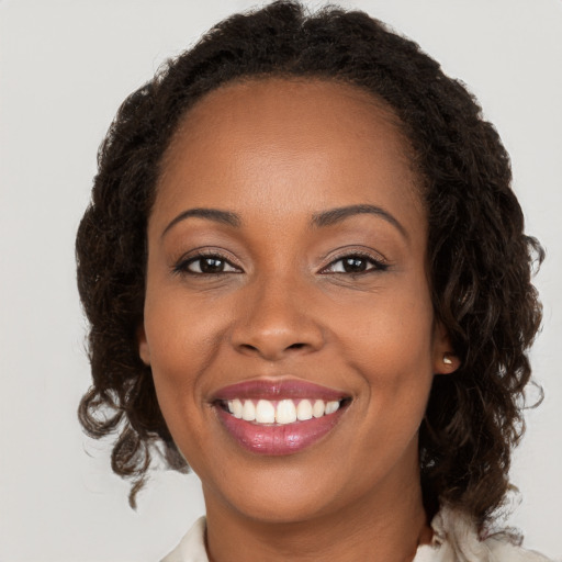 Joyful black young-adult female with long  brown hair and brown eyes