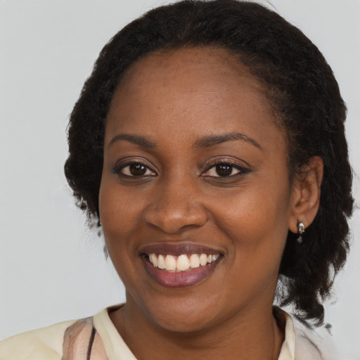 Joyful black young-adult female with long  brown hair and brown eyes