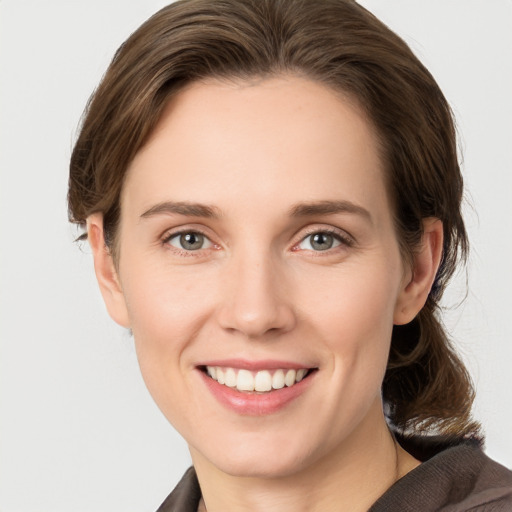 Joyful white young-adult female with medium  brown hair and grey eyes