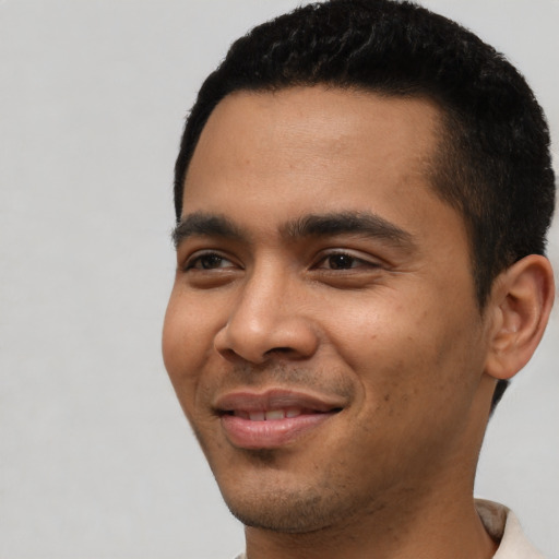 Joyful latino young-adult male with short  black hair and brown eyes