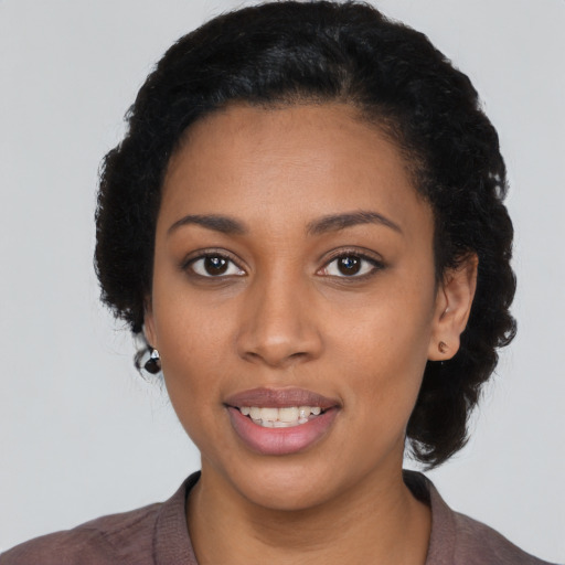 Joyful black young-adult female with short  black hair and brown eyes
