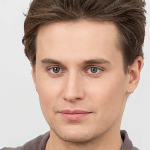 Joyful white young-adult male with short  brown hair and grey eyes