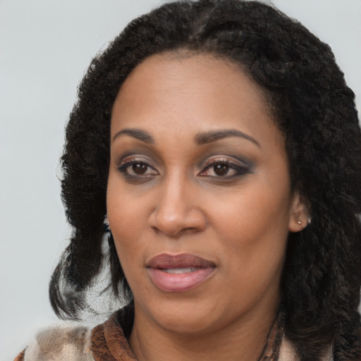 Joyful black young-adult female with long  black hair and brown eyes