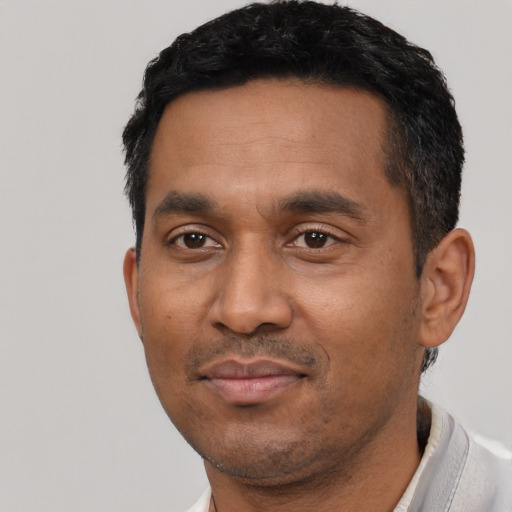 Joyful black adult male with short  black hair and brown eyes