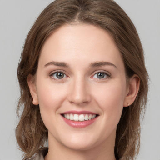 Joyful white young-adult female with medium  brown hair and grey eyes