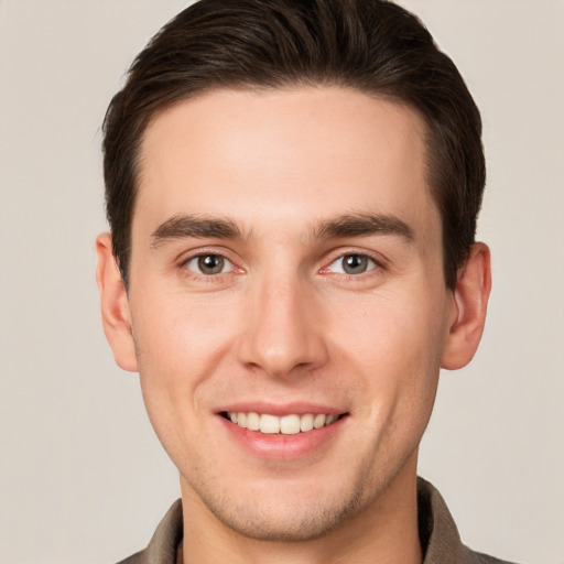 Joyful white young-adult male with short  brown hair and grey eyes