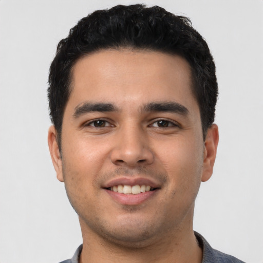 Joyful latino young-adult male with short  black hair and brown eyes