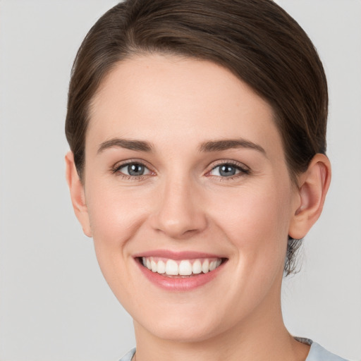 Joyful white young-adult female with short  brown hair and grey eyes