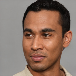 Joyful latino young-adult male with short  black hair and brown eyes