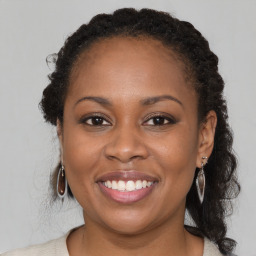 Joyful black young-adult female with long  brown hair and brown eyes