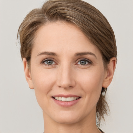 Joyful white young-adult female with medium  brown hair and grey eyes