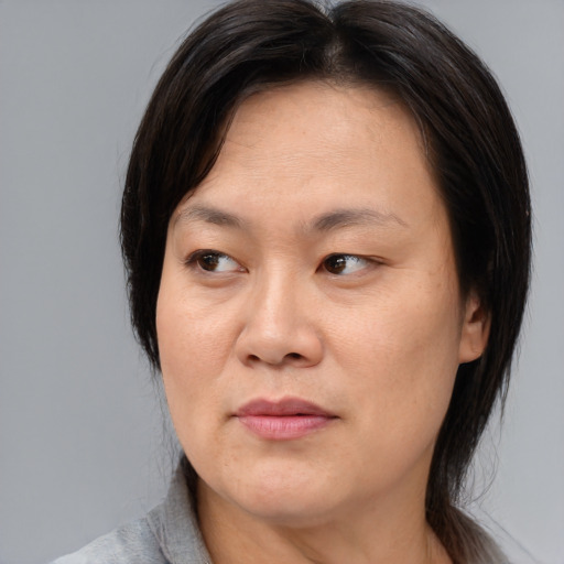 Joyful asian adult female with medium  brown hair and brown eyes