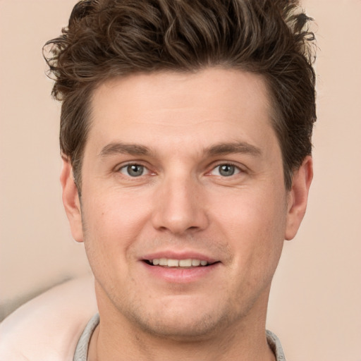 Joyful white young-adult male with short  brown hair and grey eyes