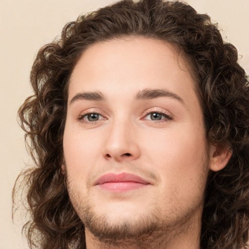 Joyful white young-adult male with long  brown hair and brown eyes