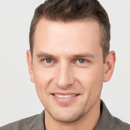 Joyful white young-adult male with short  brown hair and grey eyes