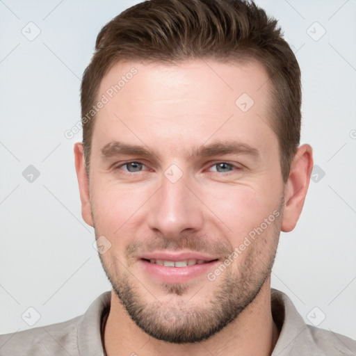 Joyful white young-adult male with short  brown hair and grey eyes