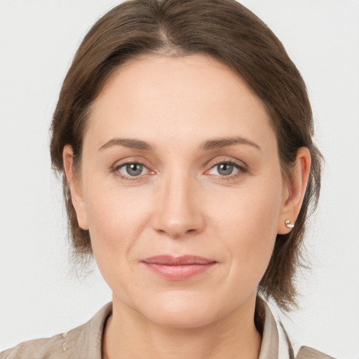 Joyful white young-adult female with medium  brown hair and grey eyes