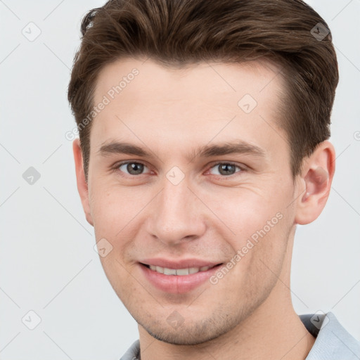 Joyful white young-adult male with short  brown hair and grey eyes