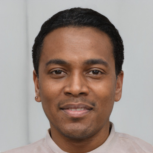 Joyful black young-adult male with short  black hair and brown eyes