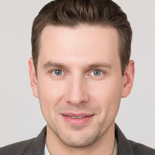 Joyful white young-adult male with short  brown hair and grey eyes