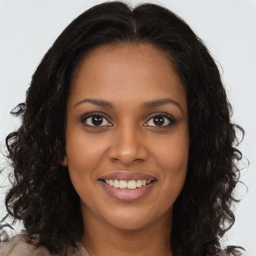 Joyful black young-adult female with long  brown hair and brown eyes