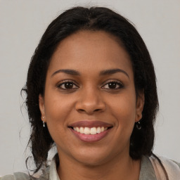 Joyful black young-adult female with long  brown hair and brown eyes