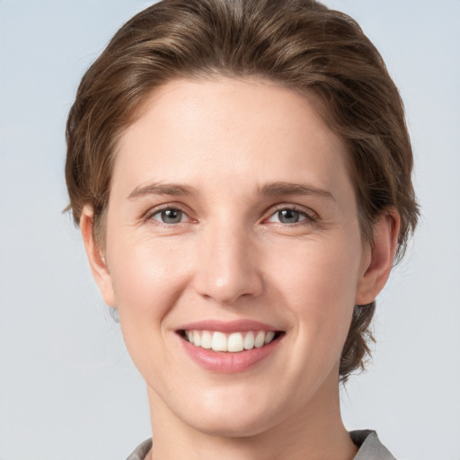 Joyful white young-adult female with medium  brown hair and grey eyes