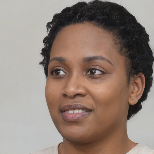Joyful black young-adult female with short  black hair and brown eyes
