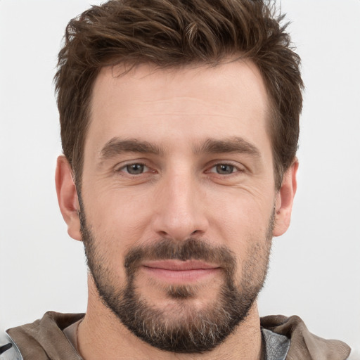 Joyful white young-adult male with short  brown hair and grey eyes