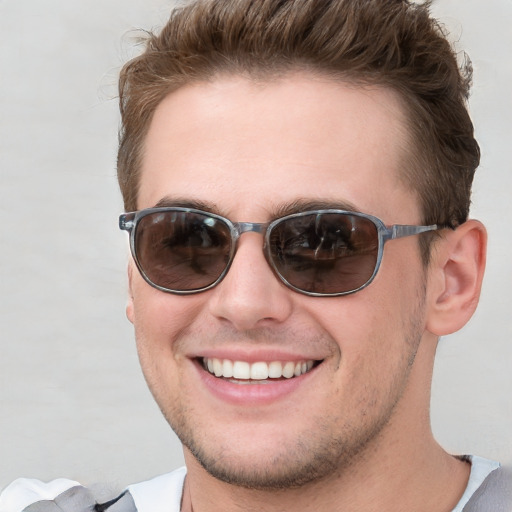 Joyful white young-adult male with short  brown hair and blue eyes