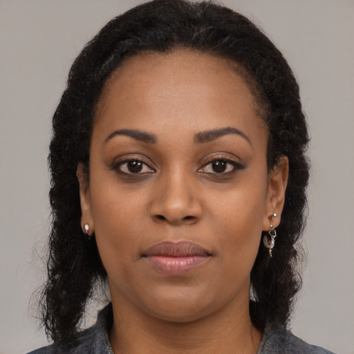 Joyful black young-adult female with long  black hair and brown eyes