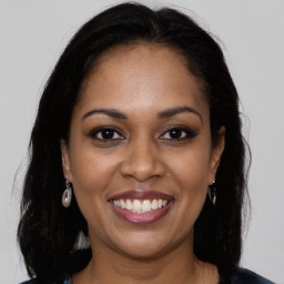 Joyful black young-adult female with long  brown hair and brown eyes