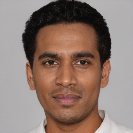 Joyful black young-adult male with short  black hair and brown eyes