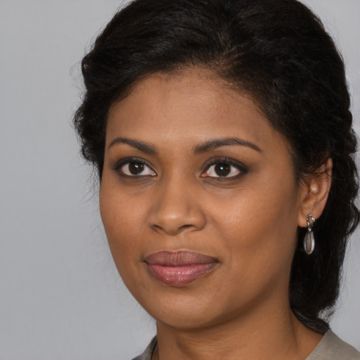 Joyful black young-adult female with long  brown hair and brown eyes