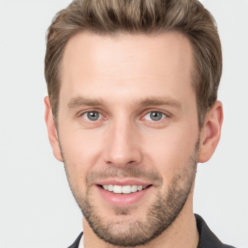 Joyful white young-adult male with short  brown hair and grey eyes