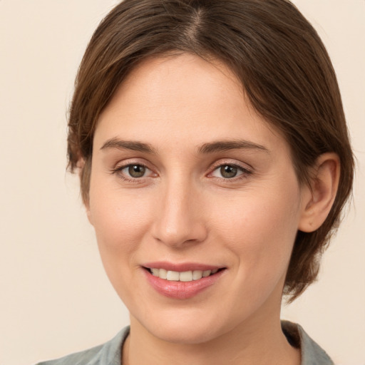 Joyful white young-adult female with medium  brown hair and grey eyes