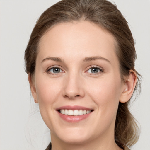 Joyful white young-adult female with medium  brown hair and grey eyes